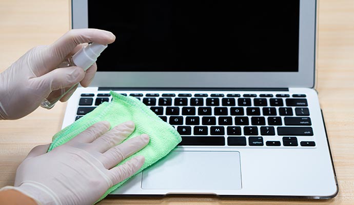 A person is disinfecting a laptop